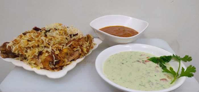 Home-cooked biryani with curry and raita